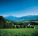 Blick über Wiesen und Dörfer zum Mondsee mit seinen Bergen im Salzkammergut