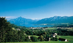 Blick über Wiesen und Dörfer zum Mondsee mit seinen Bergen im Salzkammergut
