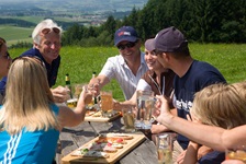 Eine Radlergruppe macht auf einer Wiese im Salzkammergut ein Picknick.