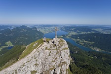 Eine Person steht auf dem Gipfel des Schafbergs und genießt die wunderbare Aussicht auf die Seenlandschaft des Salzkammergutes.