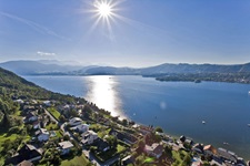 Blick über eine Gemeinde und den angrenzenden Traunsee bis hin zu den Gipfeln