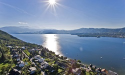Blick über eine Gemeinde und den angrenzenden Traunsee bis hin zu den Gipfeln