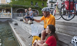Zwei Radler sitzen an der Promenade beim Wißen Rössl in St. Wolfgang - die Frau hat ihr Füße im Wasser