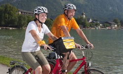 Zwei Radfahrer radeln auf einem Weg am Wolfgangsee vorbei