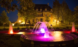 Blick auf den nächtlich rot-lila beleuchteten Brunnen und das beleuchtete Rathaus in Sarreguemines