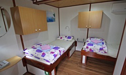 Blick in eine Zwei-Bett Kabine mit zwei Hängeschränken auf dem Deluxeschiff Harmonia