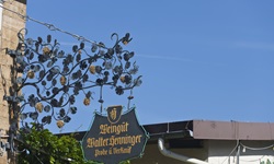 Ein eisernes Schild mit schönen Verzierungen weist auf ein Weingut hin.