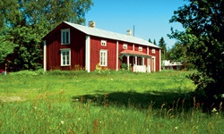 Ein schwedisches Holzhaus auf einer grünen Wiese, das rot-weiß angestrichen ist