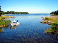 Ein Mann vertäut sein Boot in einer verträumten Bucht in Südschweden an einem Holzsteg.