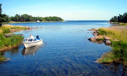 Ein Mann vertäut sein Boot in einer verträumten Bucht in Südschweden an einem Holzsteg.