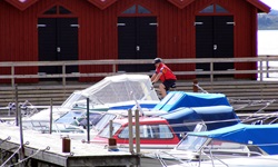 Ein Radler fährt auf einem Steg an schwedischen Bootshäusern vorbei