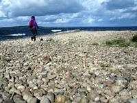 Eine Frau läuft an der Steinküste von Schweden entlang