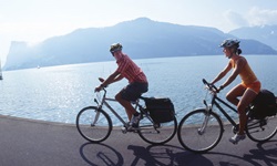 Ein Mann und eine Frau radeln auf der Schweizer Seenroute an einem See entlang.