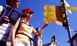 Ein Mann und eine Frau studieren anhand von Wegweisern, wie ihre Radtour auf der Schweizer Seenroute weitergeht.