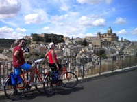 Zwei Radler stehen auf einer Brücke und genießen die Aussicht auf Caltagirone.