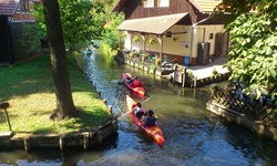 Zwei Kanus paddeln durch die Wasserstraßen des Spreewalds an Häusern vorbei