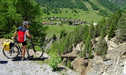 Ein Radler macht bei Zernez Pause und genießt den Ausblick auf die umliegende Bergwelt.