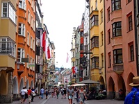 Bunte, teilweise mit Fahnen geschmückte Häuserfassaden in der Innsbrucker Innenstadt.