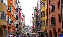 Bunte, teilweise mit Fahnen geschmückte Häuserfassaden in der Innsbrucker Innenstadt.
