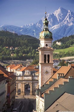 Die Alte Spitalskirche in Innsbruck vor einer herrlichen Bergkulisse.