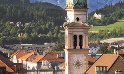 Die Alte Spitalskirche in Innsbruck vor einer herrlichen Bergkulisse.