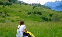 Eine Radlerin macht kurz vor dem Anstieg hinauf nach Guarda eine kurze Verschnaufpause und genießt die schöne Umgebung.