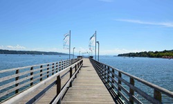 Ein hölzerner, von blau-weißen Fahnen gesäumter Steg im Starnberger See.