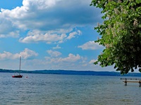 Weiße Wattewolken über dem Starnberger See im bayerischen Alpenvorland.