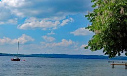 Weiße Wattewolken über dem Starnberger See im bayerischen Alpenvorland.