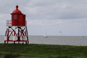 Blick von einem kleinen Leuchtturm auf das Meer in Stavoren, auf dem ein Segelboot zu sehen ist,