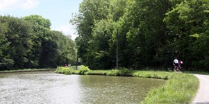 Mehrere Radfahrer radeln im Südburgund an einem Fluss entlang.