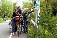Radfahrer an einer Kreuzung, die am Schild nach der richtigen Route suchen