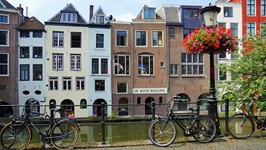 Abgestellte Räder an einer Mauer, im Hintergrund eine Häuserreihe in Utrecht