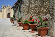 Blumenschmuck in einer romantischen Gasse, die den Blick auf eine kleine Kirche freigibt.