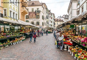Menschen schlendern über den Obst- und Blumenmarkt auf dem Piazza della Erbe in Bozen