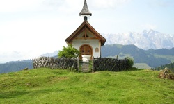 Eine idyllisch inmitten grüner Wiesen gelegene kleine Kapelle am Tauern-Radweg.