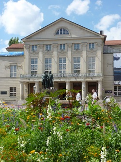 Das hinter üppigem Blumenschmuck emporragende Standbild von Schiller und Goethe in Weimar.
