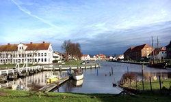 Hafen in Tönning mit zwei angelegten Booten und einem Segelschiff