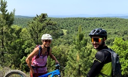 Ein Mountainbiker-Pärchen macht Pause und genießt den Ausblick auf die bewaldeten Hügel der Toskana.
