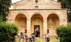 Eine Radlergruppe in der Toskana nutzt eine Pause, um eine alte Kirche zu fotografieren.