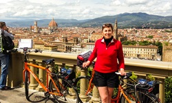 Eine Radlerin posiert vor der Skyline von Florenz für ein Foto.