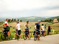 Eine Radlergruppe steht am Straßenrand und blickt in die Landschaft der Toskana