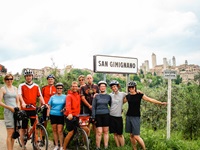 Eine Radlergruppe posiert am Ortsschild von San Gimignano in der Toskana