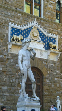 Nachbildung von Michelangelos David vor einem toskanischen Haus mit einem Ornament, das mit zwei Löwen und einer Sonne ausgestattet ist