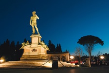 Beleuchtete Nachbildung von Michelangelos David an einem Parkplatz bei Nacht in der Toskana