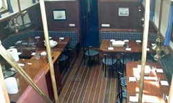 Der Innenraum mit Eckbänken, Tischen und Stühlen sowie der Bar eines Traditionsseglers
