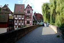Eine Steinbrücke mit Kopfsteinpflaster und Fachwerkhäusern im Fischerviertel von Ulm