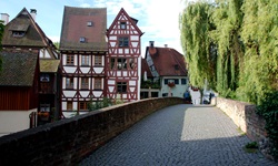 Eine Steinbrücke mit Kopfsteinpflaster und Fachwerkhäusern im Fischerviertel von Ulm