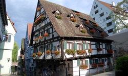 Ein Fachwerkhaus im Fischerviertel von Ulm, das an den Fenstern mit Blumen geschmückt ist