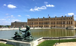 Die Statue des Meeresgottes Poseidon vor der Fassade des Prachtschlosses Versailles.